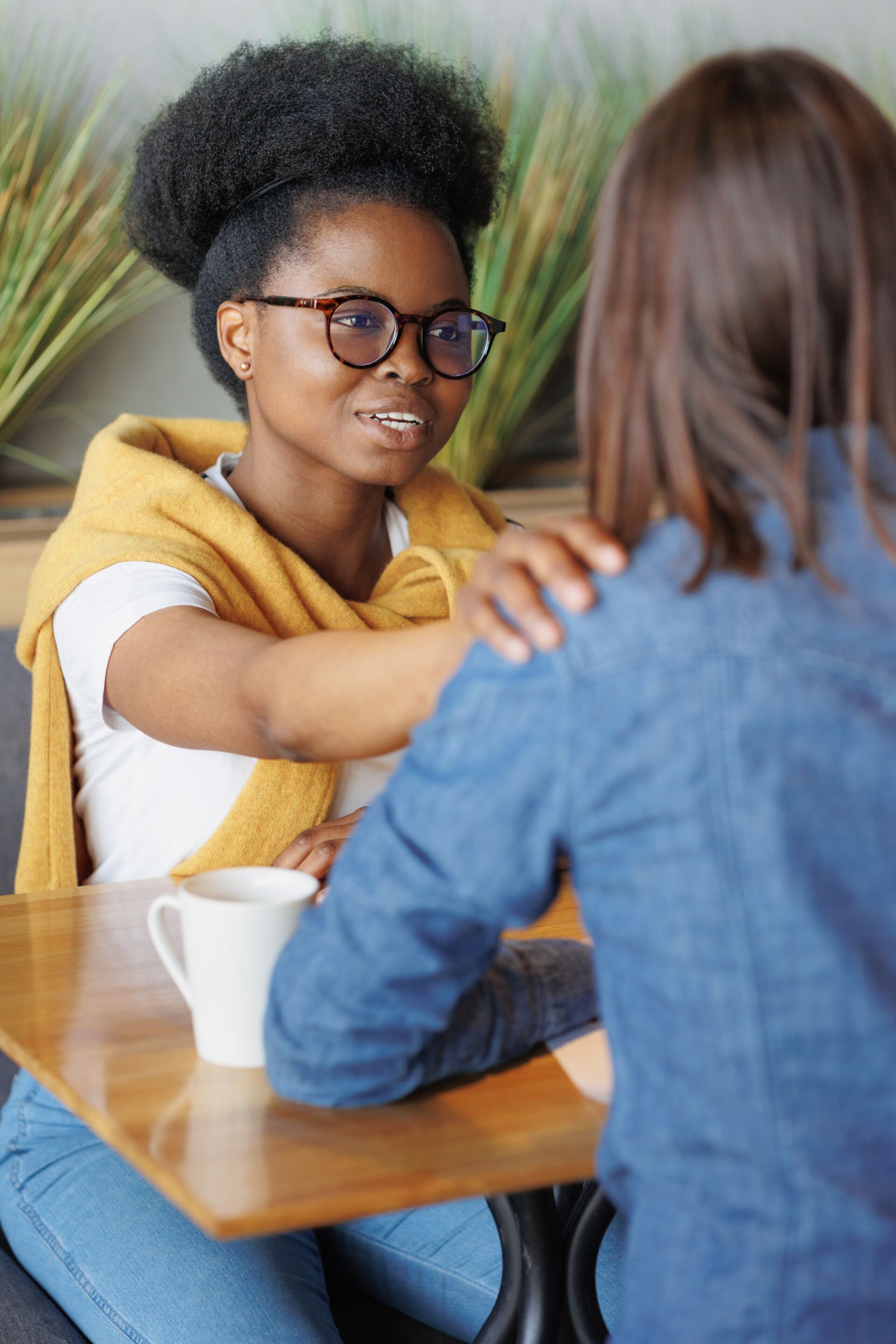 two women sitting at table talking together